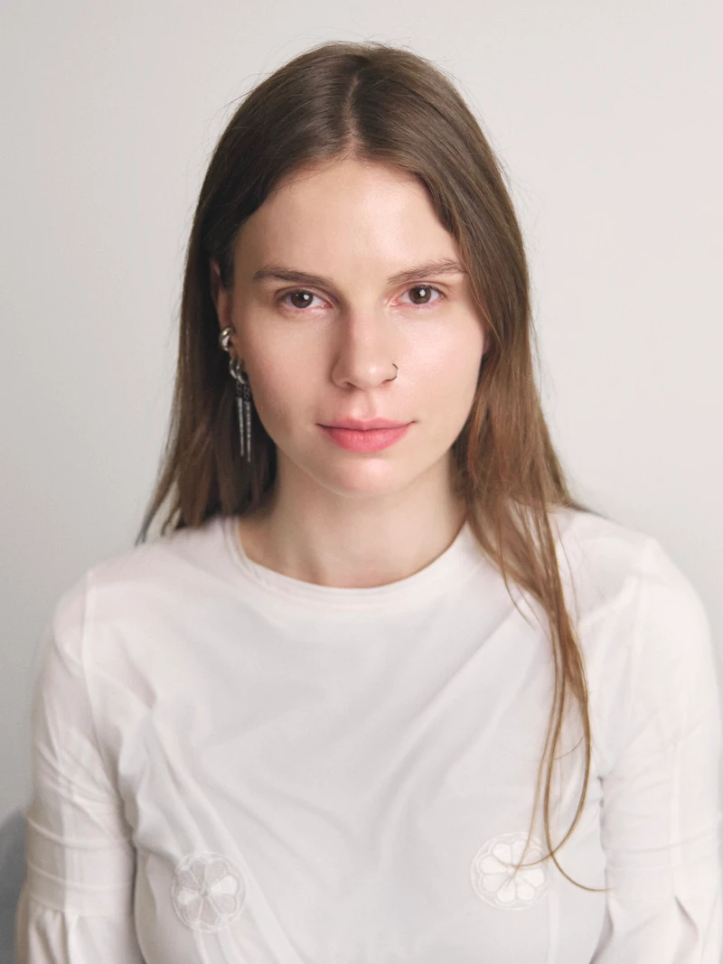 Portrait of Alina Krutakova in a white T-shirt against a light gray background