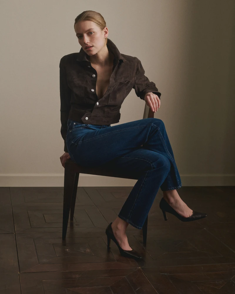 Seated model in dark shirt and blue wide-leg jeans