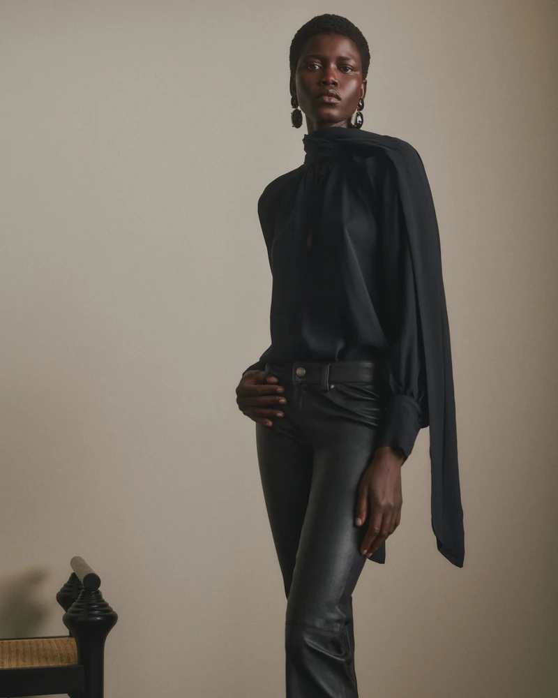 Close view of a black high-neck blouse and dark trousers