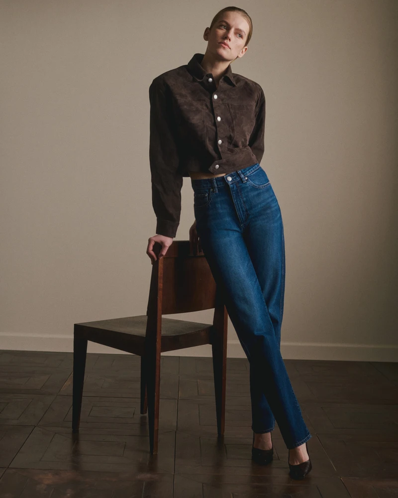 Brown cropped jacket with blue jeans in a standing portrait