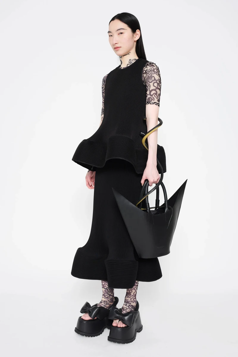 Black peplum look with patterned sleeves and a pointed tote