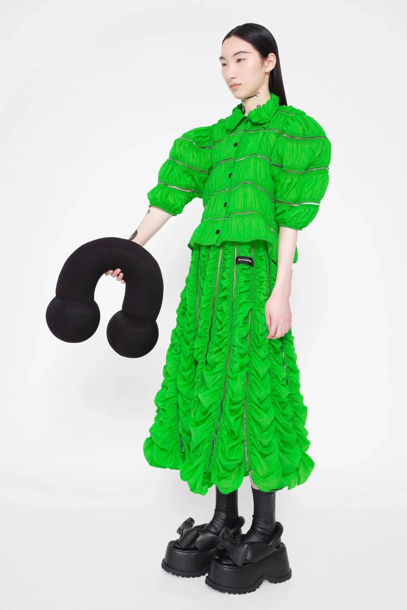 Ruched bright green dress with a curled black bag