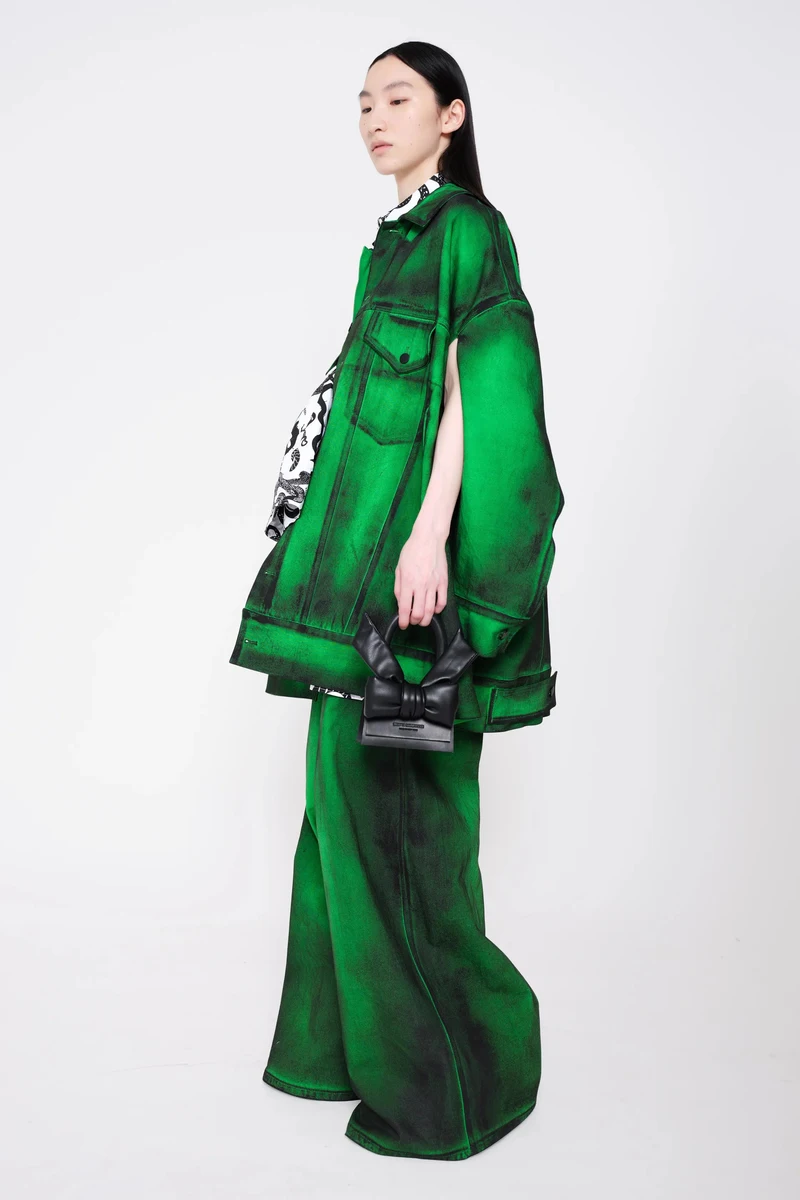 Green painted denim jacket and wide trousers with a black bow bag