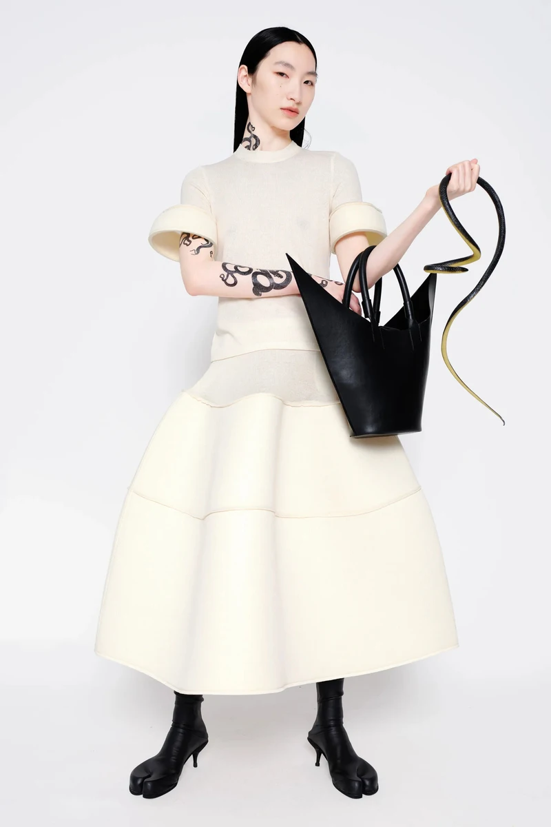 Cream sculptural skirt with a black top and pointed tote