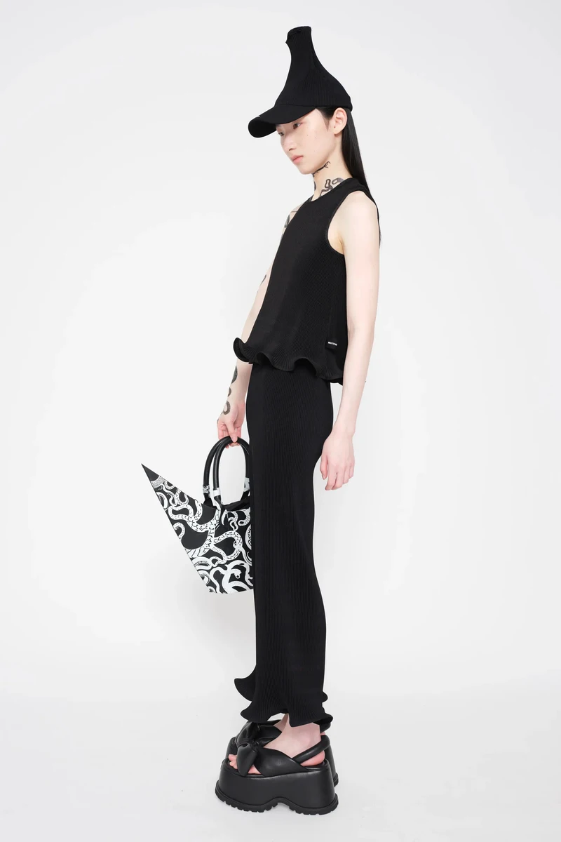 Black sleeveless look with a tall hat and patterned bag