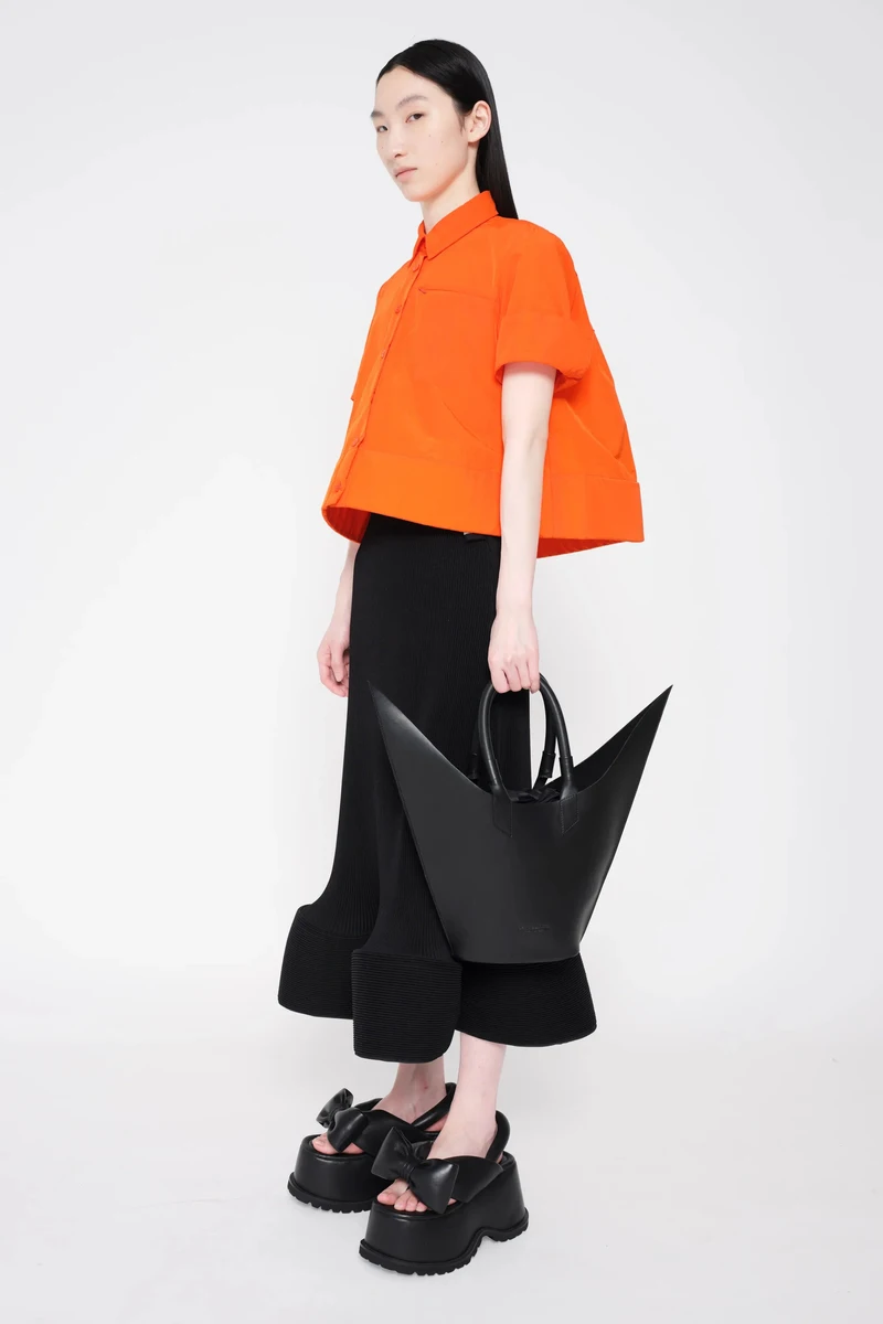 Orange cropped top and black trousers in profile