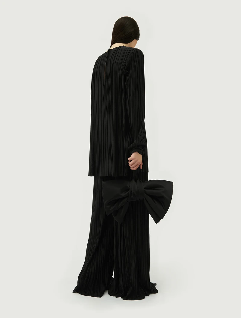 Black bow bag carried with a long black coat, rear view