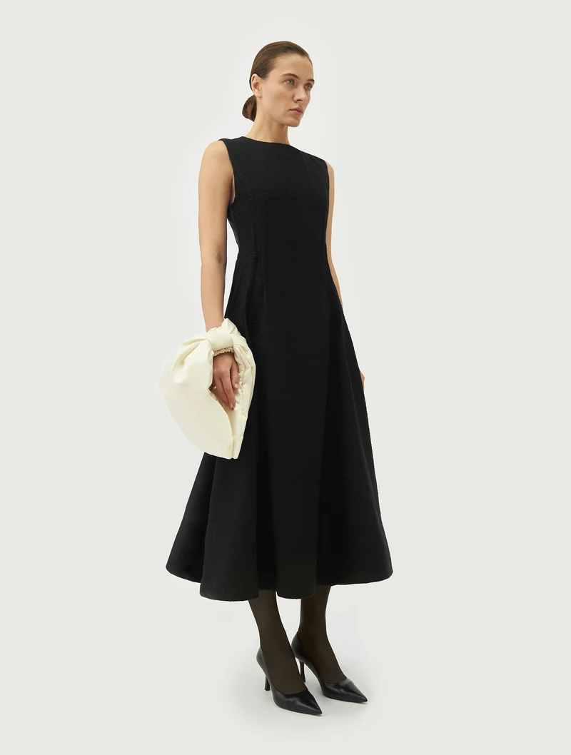 Ivory bow wrist bag worn with a black dress