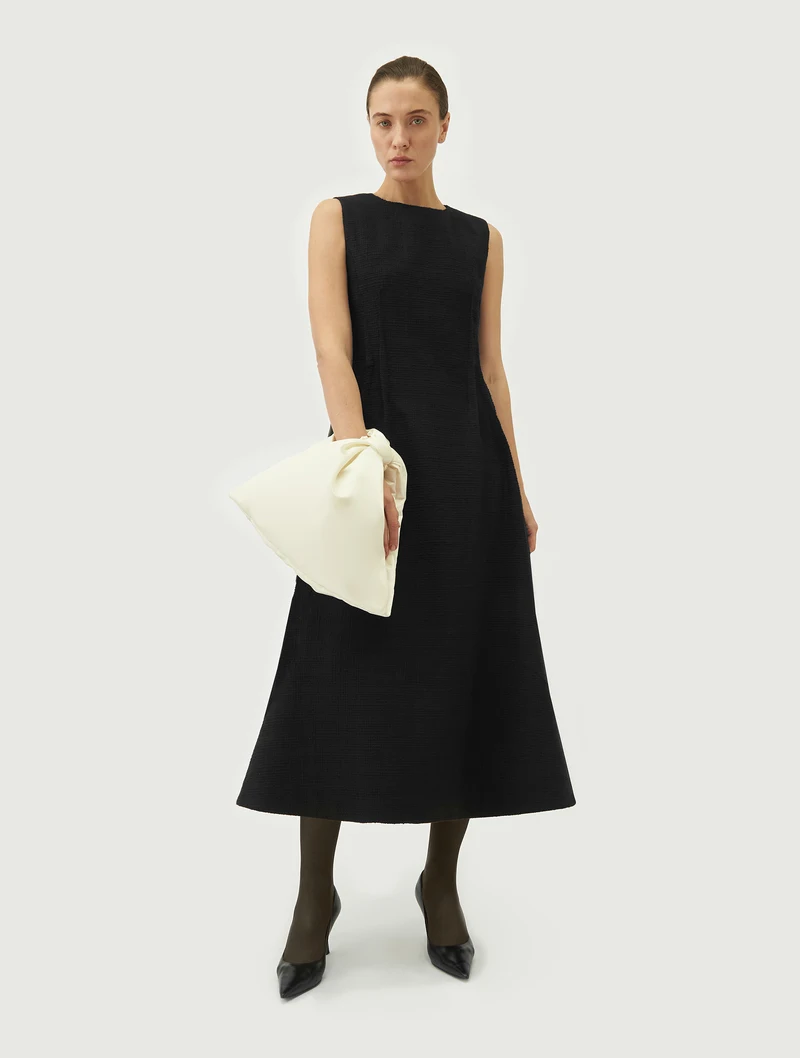 Ivory bow wrist bag carried with a black dress