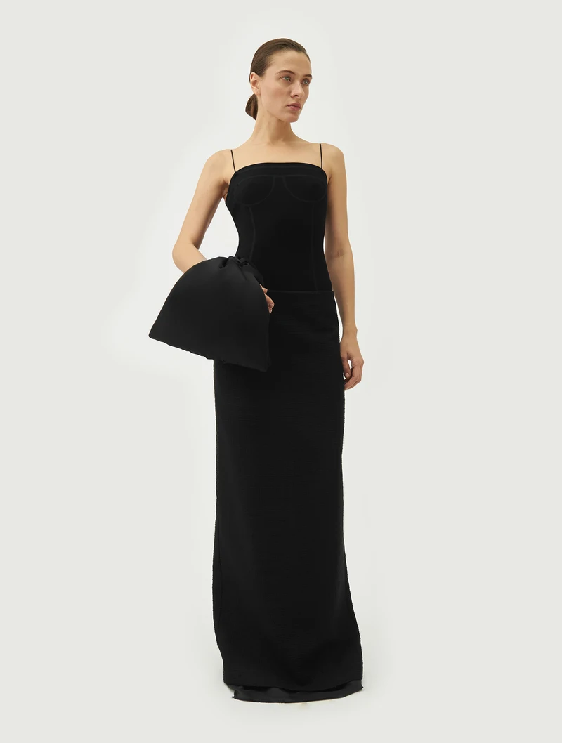 Black bow wrist bag worn with a long black dress