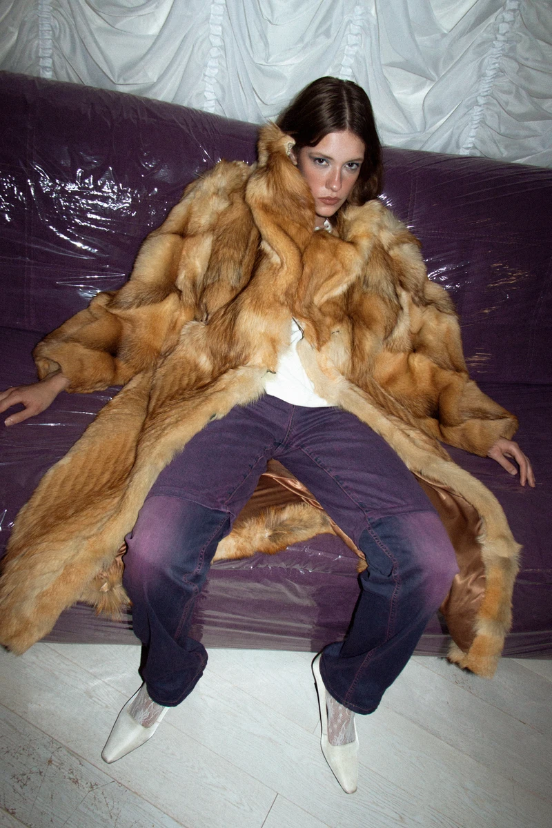 Fur coat and purple trousers on a covered sofa