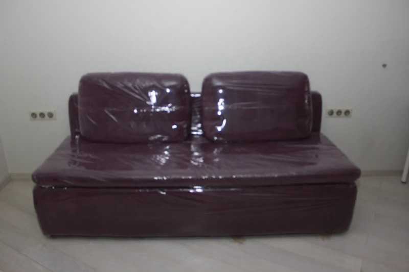 Dark purple sofa wrapped in protective plastic