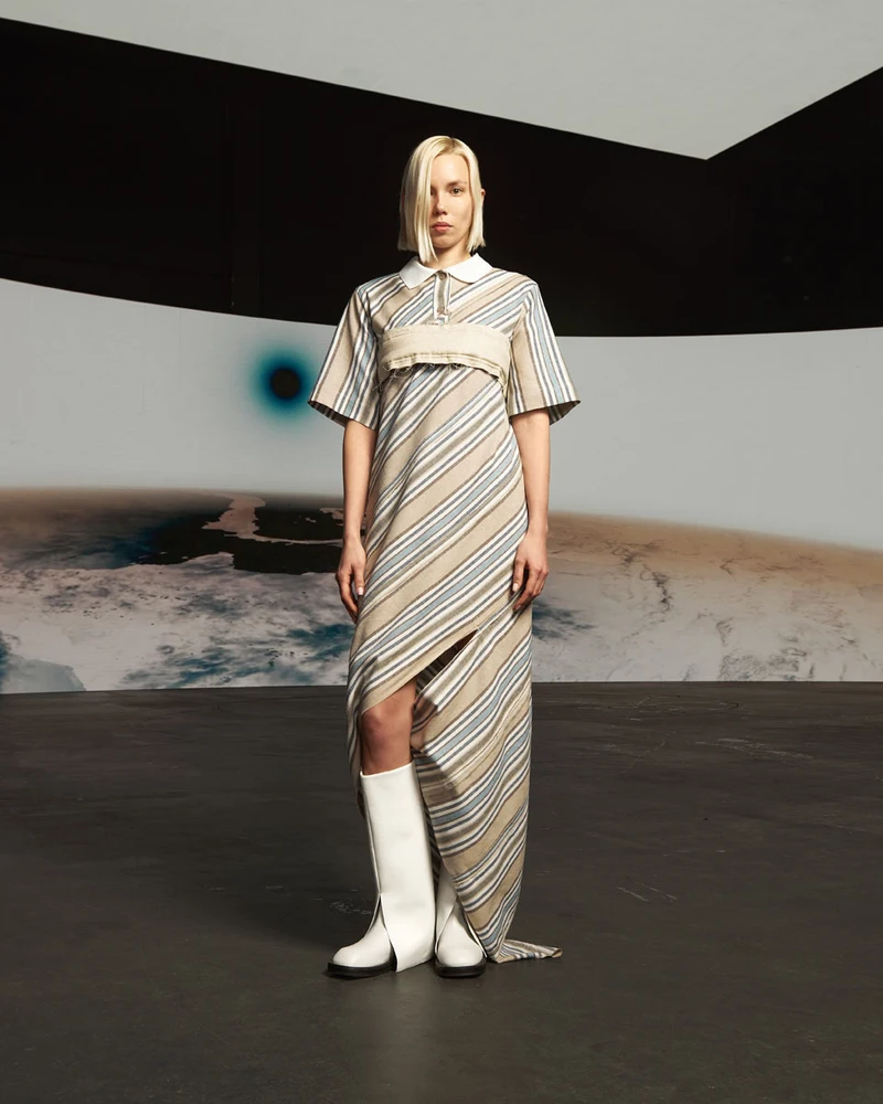 Model wearing a diagonal-striped Vertigo dress with white boots.